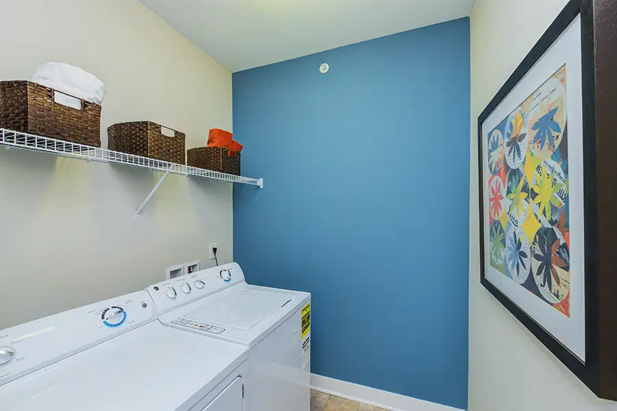 An in-unit apartment laundry room with laundry machines and a shelf